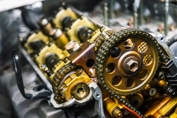 Car repair: type of open engine with drive chains and a large number of pulleys and parts. Close-up.