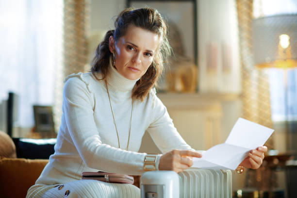 istock elegant female with utility bill near radiator 1205903626
