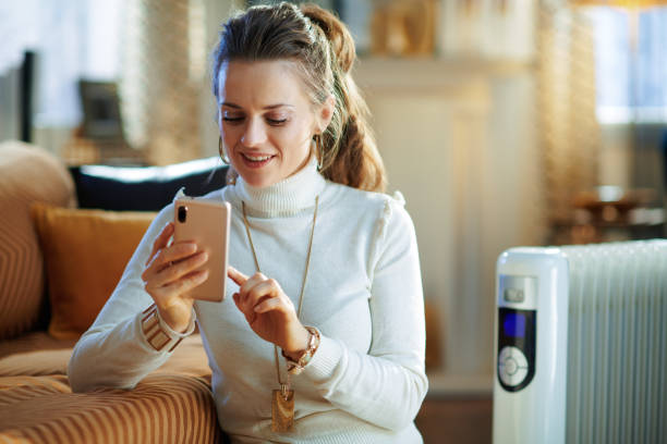 istock woman and radiator using smartphone app for temperature control 1205904764