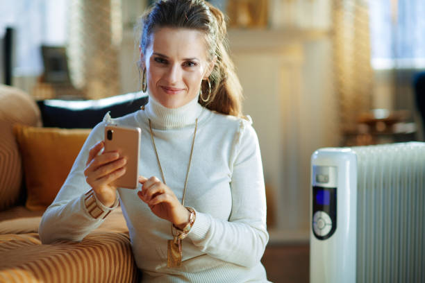 istock woman and radiator using smartphone app for temperature control 1205904805