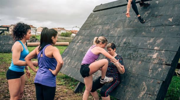 istock Female participants in obstacle course climbing pyramid obstacle 1205905132