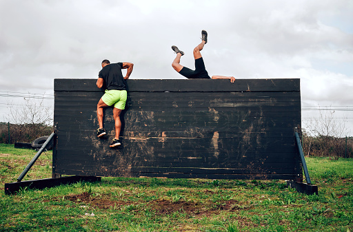 Two participants in an obstacle course climbing a wall