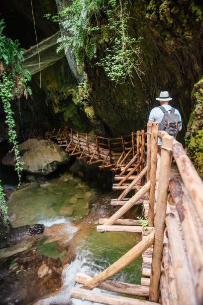 istock young strong man in white hat with backpack at cave entrance. hiking concept. creek with waterfall 1205906381