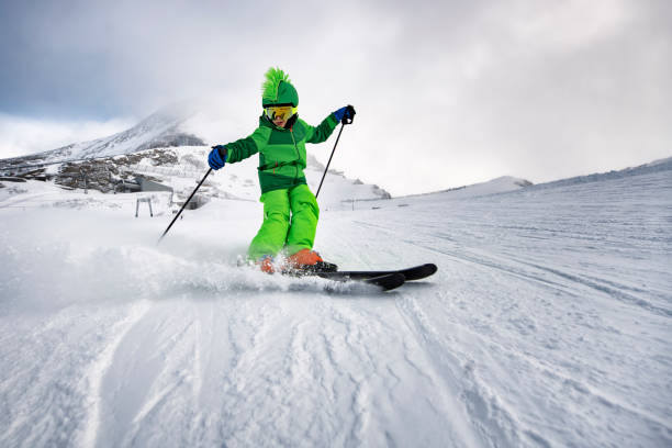 Little boy enjoying skiing at glacier in the Alps Little boys is skiing fast at glacier in the Alps. Cloudy winter day. The boy is carving right before the camera and the powder snow is spraying. alpine skiing stock pictures, royalty-free photos & images