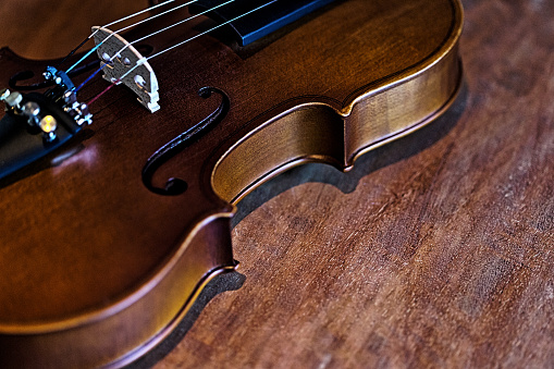 A cropped shot of a lovely old violin lying on a wooden floor.