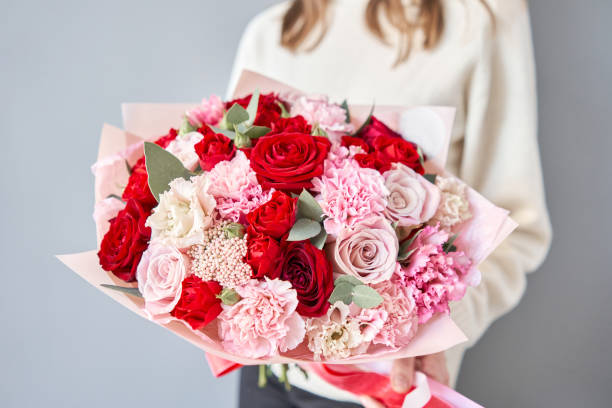 tienda de flores europea. rojo y rosa hermoso ramo de flores mixtas en manos de las mujeres. el trabajo de la floristería en una floristería. entrega flor fresca cortada. - multi colored flower red flower head fotografías e imágenes de stock