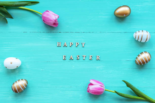 painted golden eggs and pink tulip flowers on turquoise wooden table. easter celebration concept template. top view, flat lay. - easter text single word paint imagens e fotografias de stock