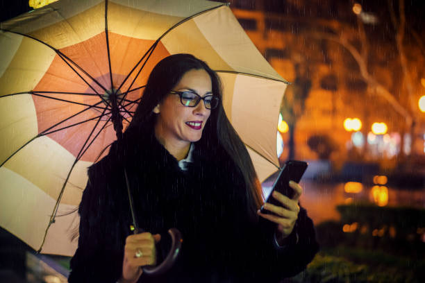 istock Woman using smartphone in the city at night 1205913898