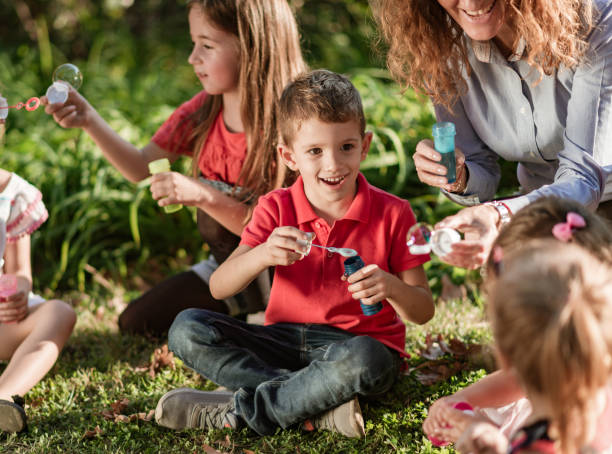 istock Happy kids blowing bubbles at public park 1205913961