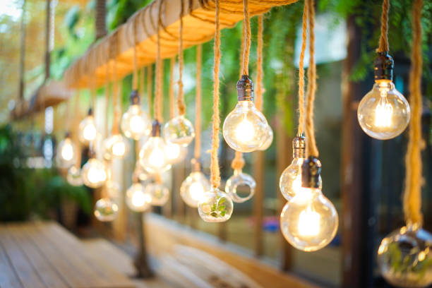 istock Decorated cozy lamps stick in the rope and little tiny tree with small white rock inside the ball glass hang on to big wood log in front of white background. 1205916851