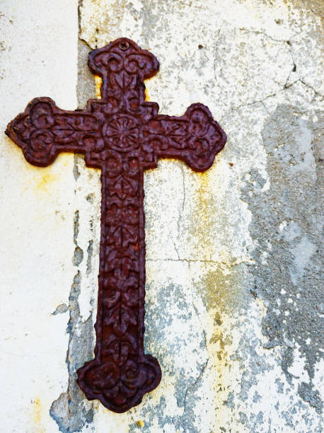 istock Rusty, neglected old metal cross botonee hanging on worn wall 1205917024