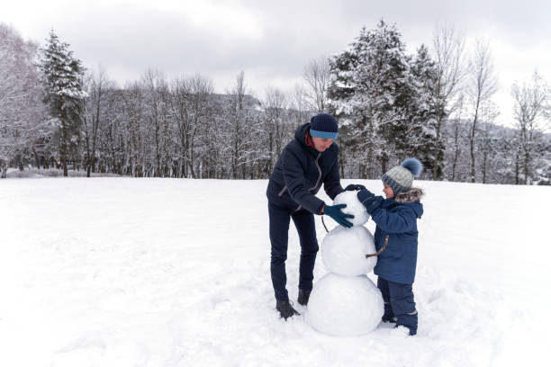 istock Dad and son makes Snowman in winter park 1205917050