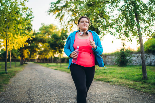 Young overweight woman running Young cute caucasian overweight woman running in a public park. pudgy woman pictures stock pictures, royalty-free photos & images