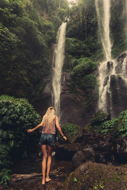 istock Young woman walking to jungle waterfall 1205920889