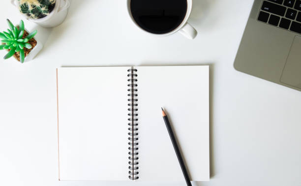 istock Flat lay, White office desk table with laptop, notebook, pencil, black coffee cup and eyeglasses. Top view with copy space. 1205923093