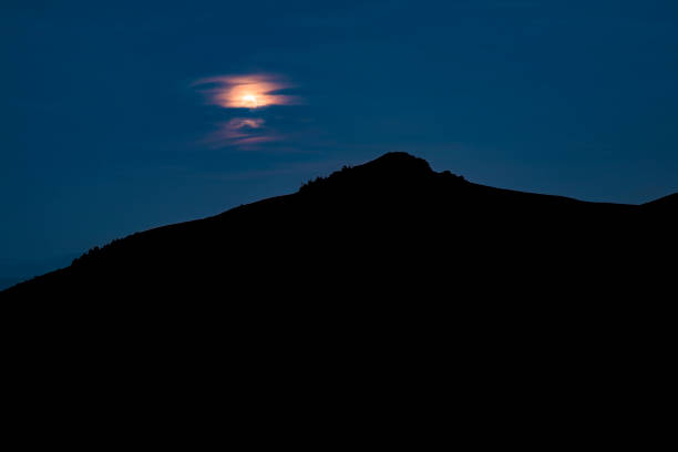 istock Black mountain silhouette time phantom blue night sky dark abstract landscape background wallpaper scenic view with unfocused moon behind clouds empty copy space for your text here 1205924812