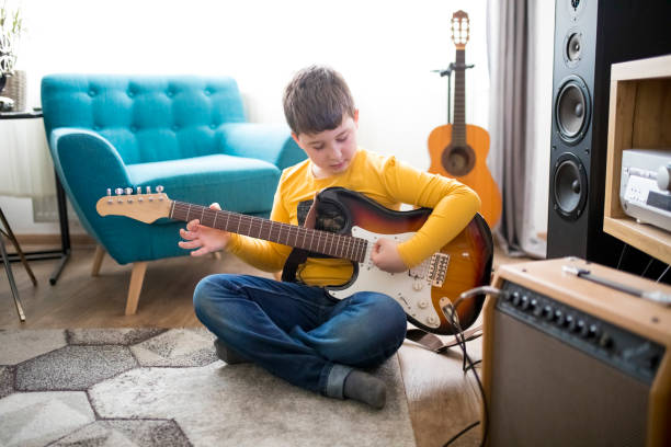 istock Little boy playing electric guitar at home 1205928918