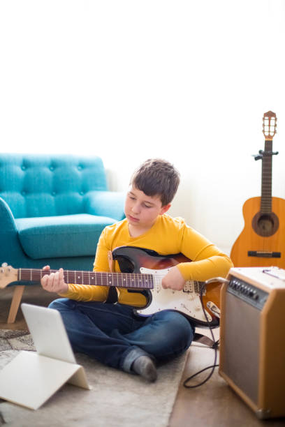 istock Little boy playing electric guitar at home 1205929382
