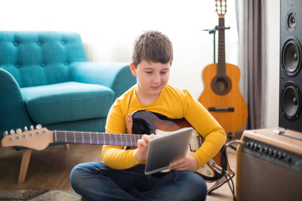 istock Little boy playing electric guitar at home 1205929758