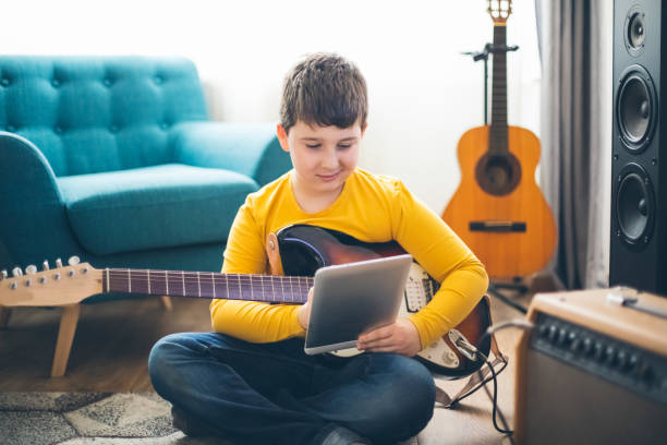 istock Little boy playing electric guitar at home 1205934862