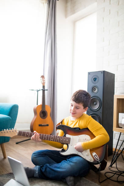 istock Little boy playing electric guitar at home 1205936156
