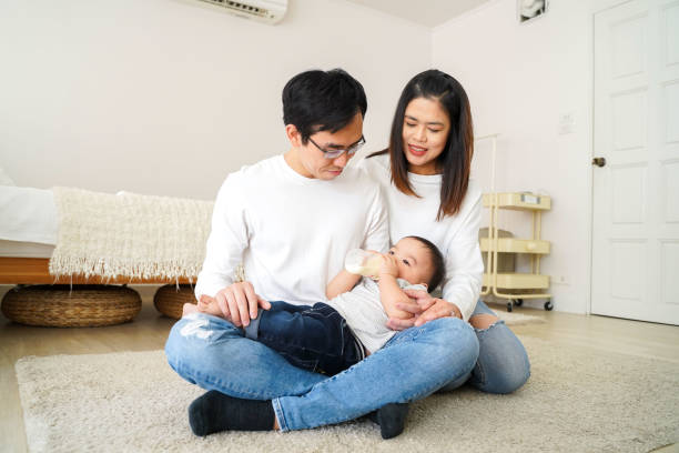 famiglia asiatica di giovane padre e madre che nutre un bambino dalla bottiglia di latte - sucking asian ethnicity baby mother foto e immagini stock