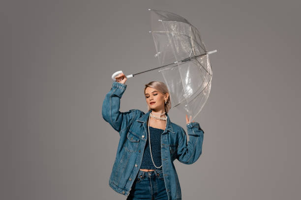 istock attractive woman in denim jacket holding umbrella isolated on grey 1205936666