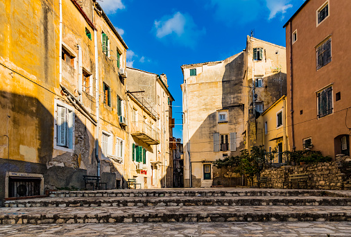 Typical street of old town Corfu city Kerkira, Greece. Sunny summer day, yellow houses, no people because of Siesta time.