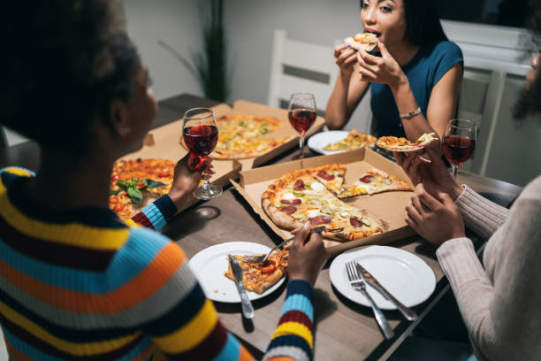 istock Girlfriends eating pizza and talking at home party 1205938631