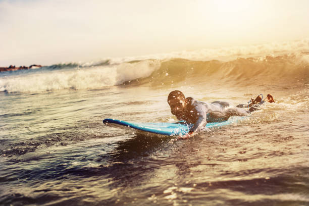 istock Handsome man has surfing on small waves. Mixed race dark skin and beard. Summer sport activity 1205939554