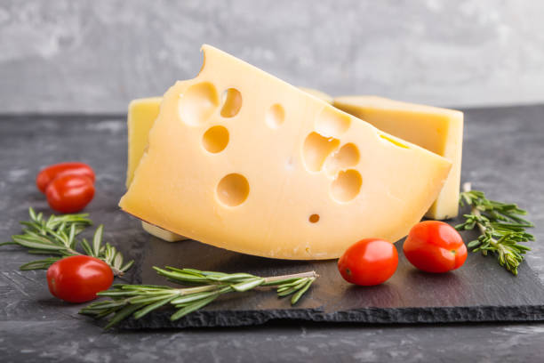 istock Various types of cheese with rosemary and tomatoes on black slate board on a black concrete background. Side view, close up, selective focus. 1205940330