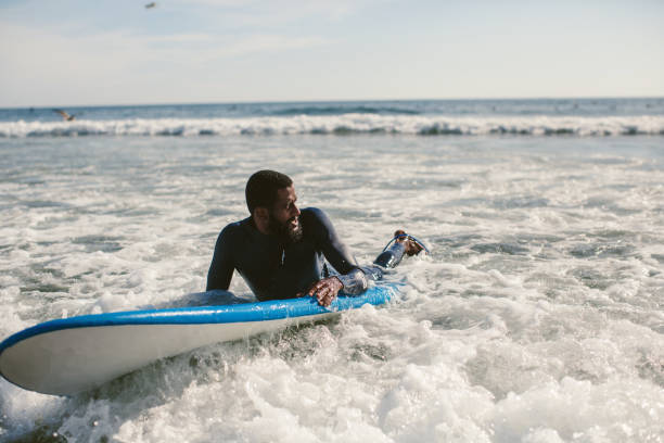 istock Handsome man has surfing on small waves. Mixed race dark skin and beard. Summer sport activity, white wash waves 1205941272