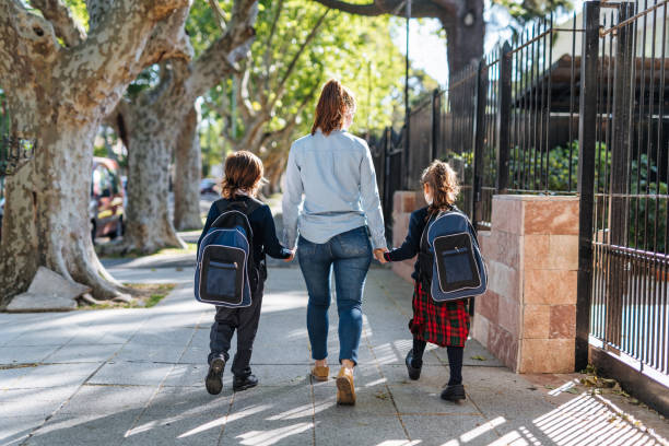istock Mother with kids going home after school 1205941809