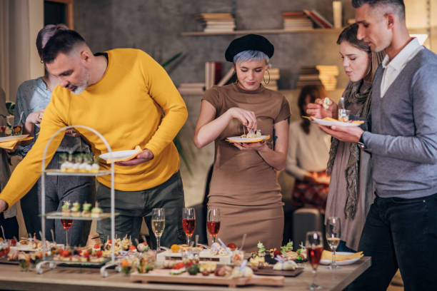 istock Business colleagues sampling savory dishes at corporate office party 1205942585