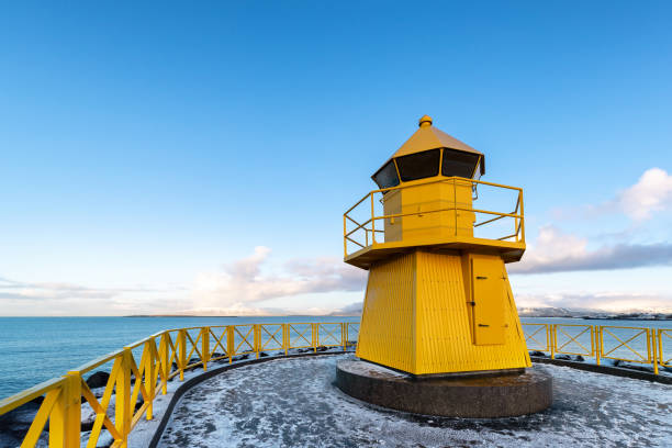 petit phare jaune sur la côte de reykjavik - security security system old blue photos et images de collection