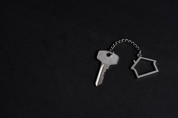 istock Home key with house keychain on black background, property agent concept, copy space 1205946160