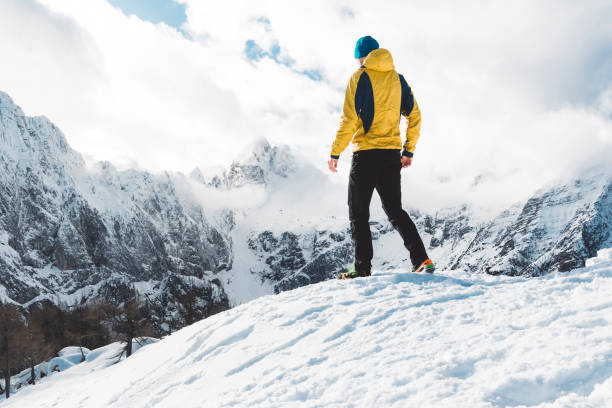 istock Hiker in yellow jacket hiking in winter 1205947538