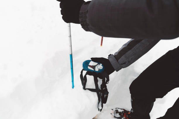 Photo taken from the perspective of a mountaineer resting at the summit of a snow-covered mountain. Bright orange crampons are visible in the foreground over the boots, while the background reveals a vast landscape of snowy peaks. The composition uses forced perspective and selective focus to evoke a sense of accomplishment and awe at the natural surroundings.