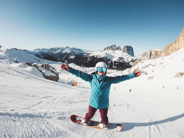 Happy woman on snow board holding her hands up in the air stock photo