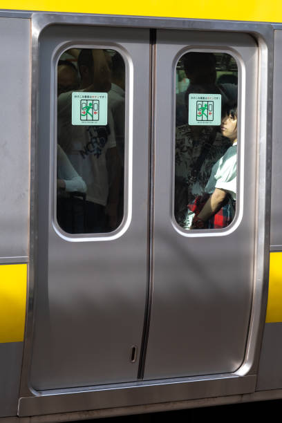 東京の地下鉄に乗っている間、女の子は憧れの外を見ます。 - longingly ストックフォトと画像