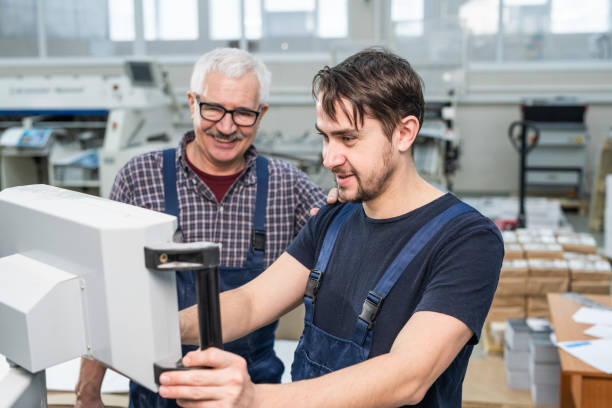 istock Young intern of printing factory operating machine 1205951776