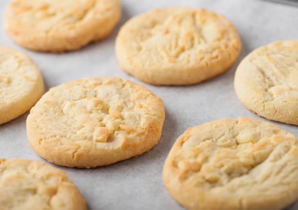 istock White chocolate biscuit cookies on baking tray on light kitchen table background. 1205952247