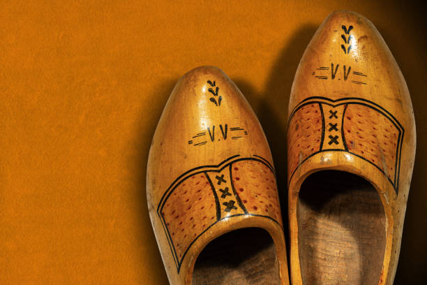 istock Pair of Dutch wooden clogs on orange background 1205952499