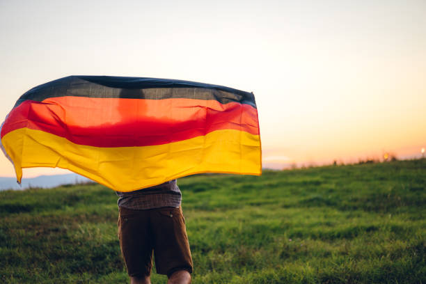 mann mit deutscher flagge auf wiese - tag der deutschen einheit stock-fotos und bilder