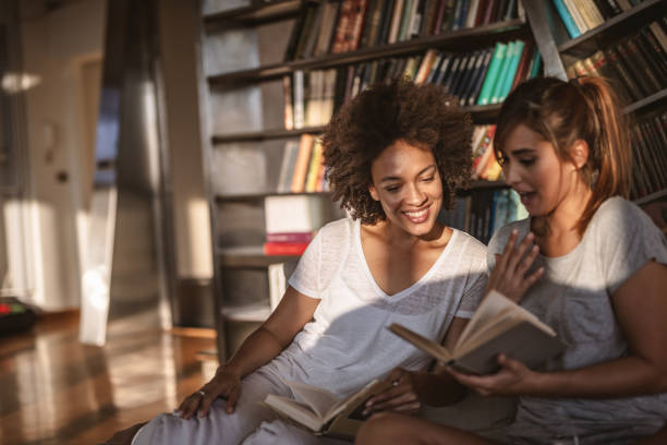 istock Female friends reading book together 1205955962