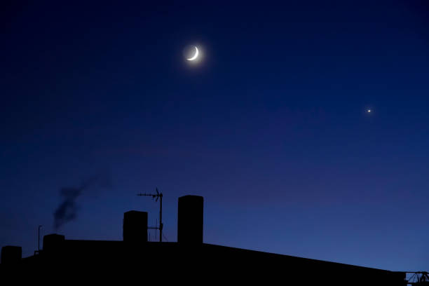 Half moon floating in the blue sky above the building
