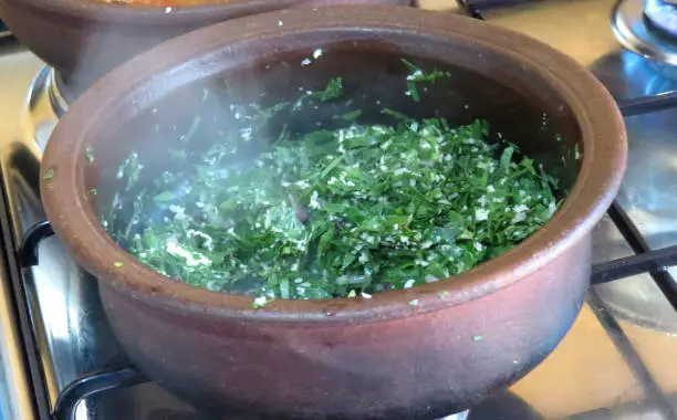 Hot green leaves been cooked on a stove