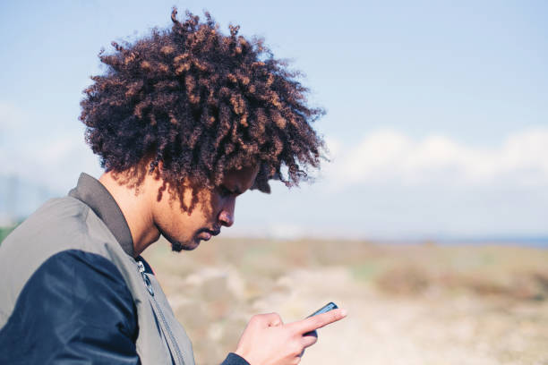 istock Young man mixed race with African hairstyle use mobile phone outdoor 1205962142