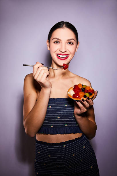 istock Smiling young woman eating a delicious fruit tart with a fork 1205963545