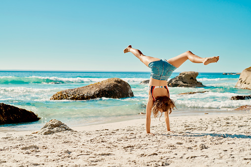 Shot of a young woman doing handstands on the beach